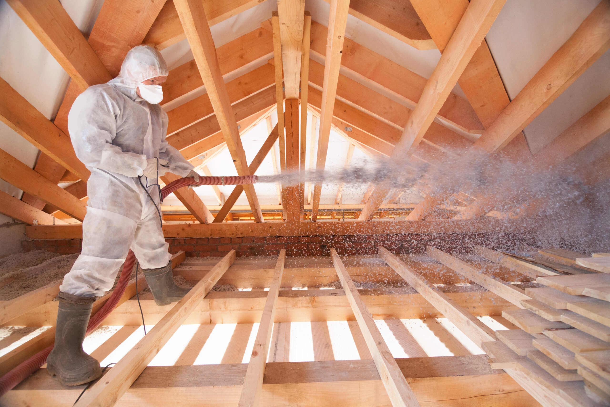 Insulation professional in protective suit spraying foam insulation in an attic