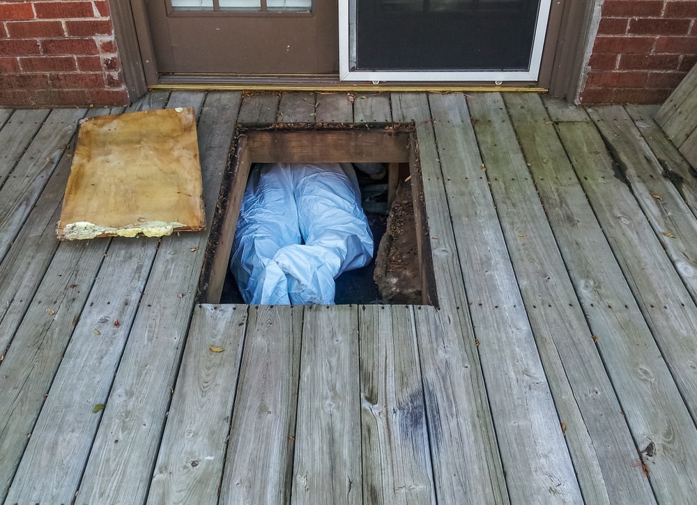 Technician in crawl space under porch