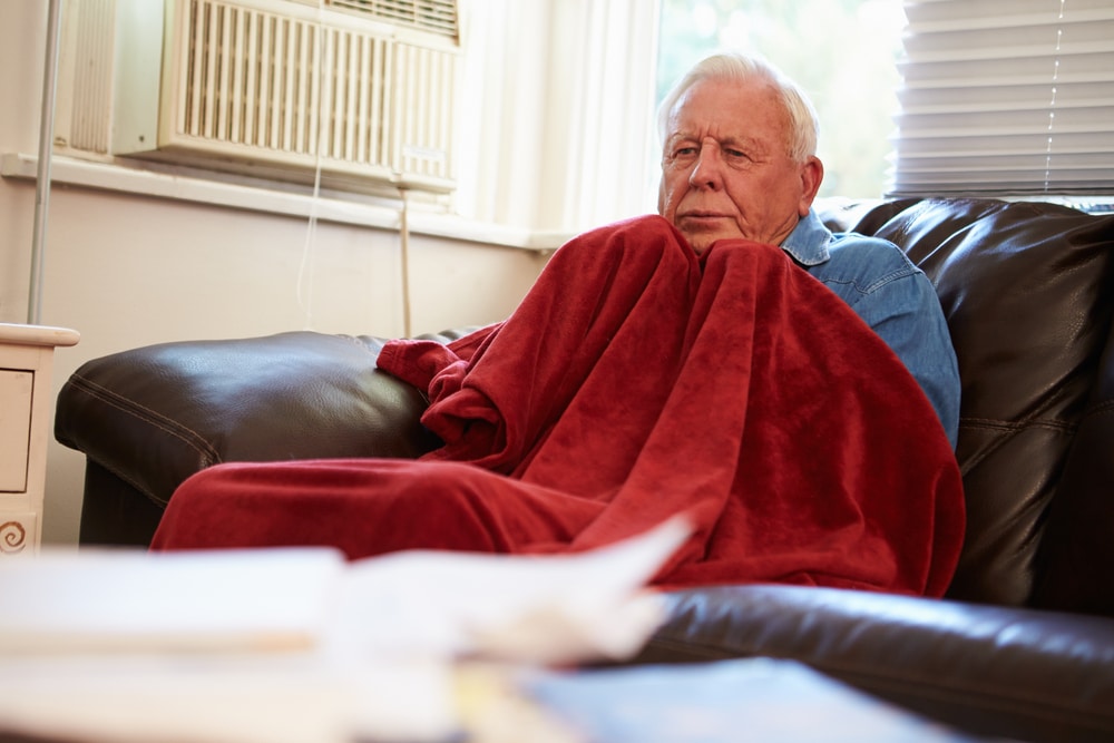 Man wrapped in blanket in chilly home